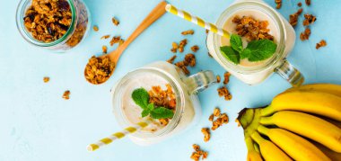 Muz smoothie granola, Kuruyemiş ve gri beton zemin üzerine nane. Üstten görünüm.