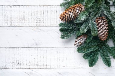 Noel süslemesi. Altın takılar, koniler, çanlar, köknar dalları ve eski beyaz tahta arka planda sunulan bayram süsleri. Sınır tasarımı. Üst Manzara. Model.