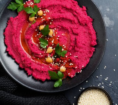 Eski karanlık beton zemin üzerine siyah seramik tabak içinde ev yapımı kırmızı pancar humus. Seçici odak. Üstten Görünüm.