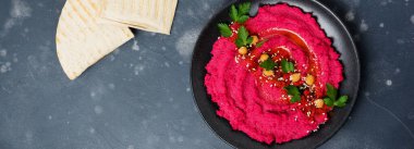 Eski karanlık beton zemin üzerine siyah seramik tabak içinde ev yapımı kırmızı pancar humus. Seçici odak. Üstten Görünüm.