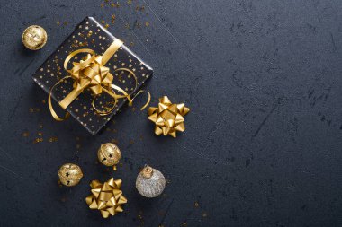 Tatil hediyesi kutusu ya da kurdele, altın konfeti ve siyah arka planda altın takılar. Sihirli Noel tebrik kartı. Noel süslemesi. Sınır tasarımı. Model yap. Üst görünüm.