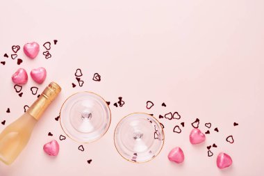 Sevgililer günü tebrik kartı, şampanya şişesi, çekici gözlükleri, çikolata kalpleri ve pembe arka planda hediye kutusu. Selamlaşmak için en iyi manzara. Kopyalama alanı olan tebrik kartı.