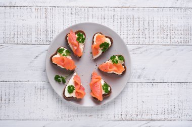 Somonlu mini sandviç, peynirli peynir, maydanoz ve kalp şeklinde çavdar ekmeği. Sevgililer Günü ev yapımı yaratıcı yemekler. Kahvaltı tasarımına bayılırım. Seçici odak ve kopyalama alanı