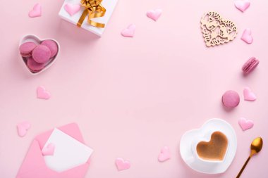 Valentines Day card. Pink empty envelope, macaron macaroon cookie and heart shaped coffee cup on pink background. 8 March, Womens Mothers Valentines Day, Birthday. Flat lay, top view, copy space.