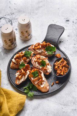 Peynirli Chanterelle sandviçi. Açık yüzlü sandviç, krem peynirli, baharatlı, biberli ve eski ahşap arka planda taze maydanozlu. Model yap. Üst görünüm.