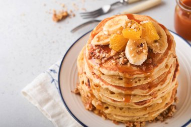 Krepler. Hafif beton zeminde kahvaltıda muz, ceviz ve karamel ile ev yapımı pofuduk krep. Geleneksel Amerikan kahvaltısı için leziz krepler. Seçici odaklanma. Model.