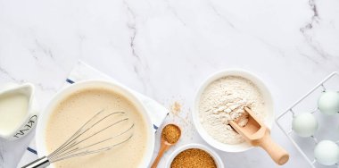 Kahvaltı ya da Maslenitsa için ev krepleri için hamur hazırlama. Masadaki malzemeler - buğday unu, yumurta, tereyağı, şeker, tuz, süt. Adım adım tarif et. Metin için yeri olan üst görünüm.