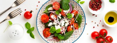 Domates, ıspanak yaprakları, kırmızı soğan ve beyaz peynirli salata hafif bir seramik tabak. Seçici odak. Üstten görünüm.