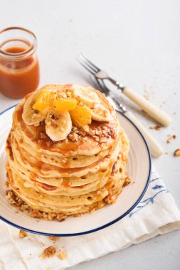 Krepler. Hafif beton zeminde kahvaltıda muz, ceviz ve karamel ile ev yapımı pofuduk krep. Geleneksel Amerikan kahvaltısı için leziz krepler. Seçici odaklanma. Model.