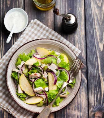 Marul, elma, kereviz, soğan ve tavuklu salata koyu ahşap arka planda..