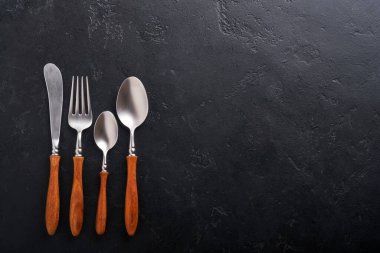 Klasik çatal bıçak takımı. Siyah arka planda ahşap kaşık ve çatal. Üst Manzara. Model.