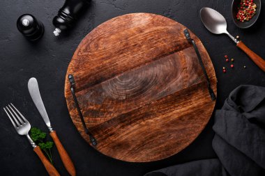 Klasik çatal bıçak takımı. Siyah arka planda ahşap tabakta ahşap kaşık ve çatal. Boş tabaklar. Üst Manzara. Model.