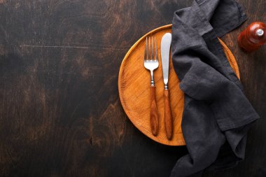 Klasik çatal bıçak takımı. Siyah ahşap arka planda ahşap tabakta ahşap kaşık ve çatal. Boş tabaklar. Üst Manzara. Model.