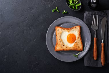 Sevgililer Günü 'nde kahvaltı. Kalp şeklinde sahanda yumurta ve ekmek ve siyah arka planda taze sebze. Sevdikleri için sürpriz kahvaltı. Üst Manzara. Model.