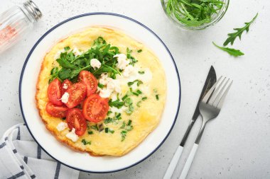 Kahvaltıda yağda yumurta. Yeşil soğanlı omlet, peynirli mozzarella, yeşil roka ve hafif taşlı domatesli omlet. Sağlıklı gıda konsepti. Uzayı kopyala Üst Manzara. Model.