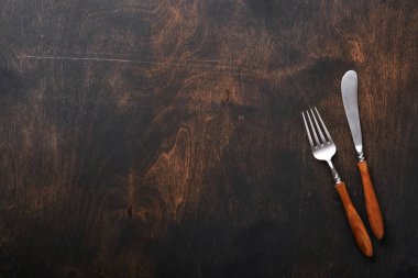 Klasik çatal bıçak takımı. Siyah ahşap arka planda ahşap kaşık ve çatal kullanılmış. Boş tabaklar. Üst Manzara. Model.
