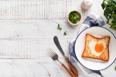 Kalp şeklinde yumurtalı tost ve açık beyaz ahşap arka planda mikro yeşillikler, kahvaltı masası üstü. Sevgililer Günü kahvaltısı. Üst Manzara. Model.