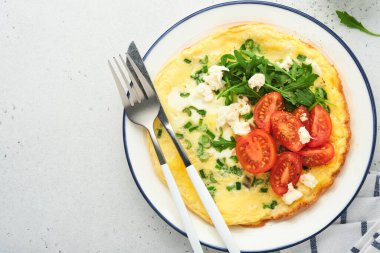 Kahvaltıda yağda yumurta. Yeşil soğanlı omlet, peynirli mozzarella, yeşil roka ve hafif taşlı domatesli omlet. Sağlıklı gıda konsepti. Uzayı kopyala Üst Manzara. Model.