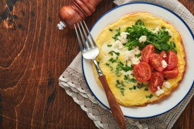 Köy usulü omlet ya da yeşil soğanlı frittata peynirli mozzarella, yeşil roka ve eski ahşap arka planda domatesler. Sağlıklı gıda konsepti. Kahvaltıda. Uzayı kopyala Üst Manzara. Model.