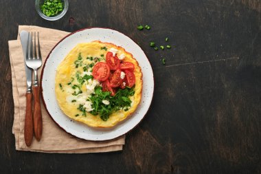 Köy usulü omlet ya da yeşil soğanlı frittata peynirli mozzarella, yeşil roka ve eski ahşap arka planda domatesler. Sağlıklı gıda konsepti. Kahvaltıda. Uzayı kopyala Üst Manzara. Model.
