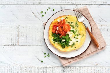 Yeşil soğanlı omlet veya frittata, peynir mozzarella, yeşil roka ve eski ahşap arka planda domates. Sağlıklı gıda konsepti. Kahvaltıda. Uzayı kopyala Üst Manzara. Model.