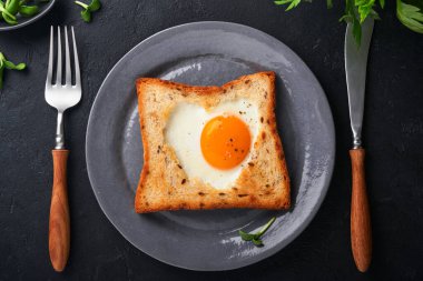 Sevgililer Günü 'nde kahvaltı. Kalp şeklinde sahanda yumurta ve ekmek ve siyah arka planda taze sebze. Sevdikleri için sürpriz kahvaltı. Üst Manzara. Model.