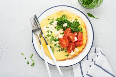 Kahvaltıda yağda yumurta. Yeşil soğanlı omlet, peynirli mozzarella, yeşil roka ve hafif taşlı domatesli omlet. Sağlıklı gıda konsepti. Uzayı kopyala Üst Manzara. Model.