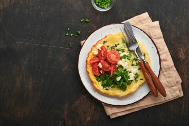 Köy usulü omlet ya da yeşil soğanlı frittata peynirli mozzarella, yeşil roka ve eski ahşap arka planda domatesler. Sağlıklı gıda konsepti. Kahvaltıda. Uzayı kopyala Üst Manzara. Model.