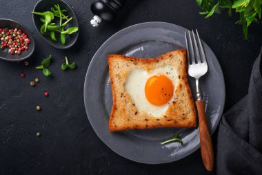 Sevgililer Günü 'nde kahvaltı. Kalp şeklinde sahanda yumurta ve ekmek ve siyah arka planda taze sebze. Sevdikleri için sürpriz kahvaltı. Üst Manzara. Model.