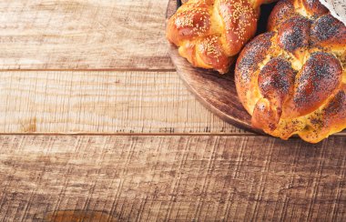 Şabat Şalom. Susam tohumlu ekmek, ahşap arka planda haşhaş tohumu. Geleneksel Yahudi ekmeği Şabat ve Tatil için. Kaba bir kavram. Uzayı kopyala Seçici odak.