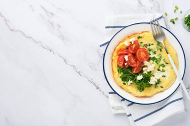 Kahvaltıda yağda yumurta. Yeşil soğanlı omlet, peynirli mozzarella, yeşil roka ve hafif taşlı domatesli omlet. Sağlıklı gıda konsepti. Uzayı kopyala Üst Manzara. Model.