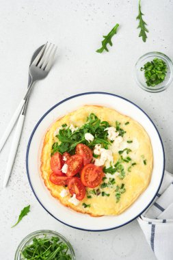 Kahvaltıda yağda yumurta. Yeşil soğanlı omlet, peynirli mozzarella, yeşil roka ve hafif taşlı domatesli omlet. Sağlıklı gıda konsepti. Uzayı kopyala Üst Manzara. Model.
