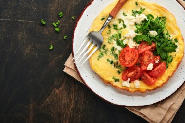 Köy usulü omlet ya da yeşil soğanlı frittata peynirli mozzarella, yeşil roka ve eski ahşap arka planda domatesler. Sağlıklı gıda konsepti. Kahvaltıda. Uzayı kopyala Üst Manzara. Model.