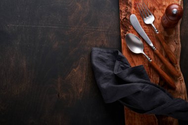 Klasik çatal bıçak takımı. Siyah ahşap arka planda ahşap tabakta ahşap kaşık ve çatal. Boş tabaklar. Üst Manzara. Model.