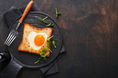 Sevgililer Günü kahvaltısı. Kalp şeklinde kızarmış yumurta ve ekmek ve eski ahşap arka planda taze sebzeler. Sevdikleri için sürpriz kahvaltı. Model.