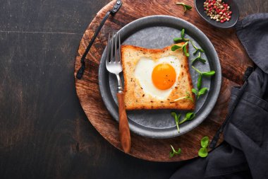 Sevgililer Günü kahvaltısı. Kalp şeklinde kızarmış yumurta ve ekmek ve eski ahşap arka planda taze sebzeler. Sevdikleri için sürpriz kahvaltı. Model.