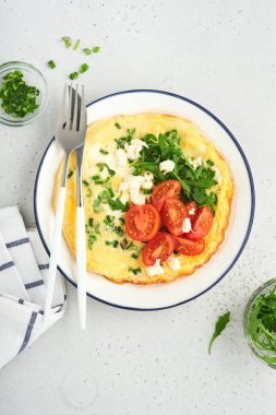 Kahvaltıda yağda yumurta. Yeşil soğanlı omlet, peynirli mozzarella, yeşil roka ve hafif taşlı domatesli omlet. Sağlıklı gıda konsepti. Uzayı kopyala Üst Manzara. Model.