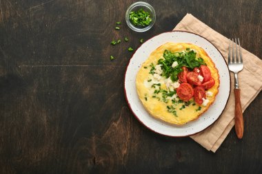 Köy usulü omlet ya da yeşil soğanlı frittata peynirli mozzarella, yeşil roka ve eski ahşap arka planda domatesler. Sağlıklı gıda konsepti. Kahvaltıda. Uzayı kopyala Üst Manzara. Model.