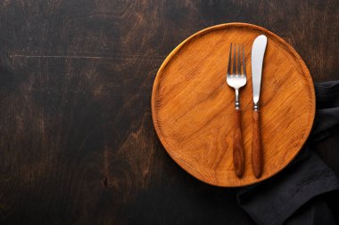 Klasik çatal bıçak takımı. Siyah ahşap arka planda ahşap tabakta ahşap kaşık ve çatal. Boş tabaklar. Üst Manzara. Model.