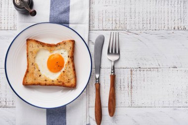 Kalp şeklinde yumurtalı tost ve açık beyaz ahşap arka planda mikro yeşillikler, kahvaltı masası üstü. Sevgililer Günü kahvaltısı. Üst Manzara. Model.