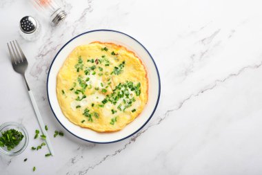 Yeşil soğanlı omlet veya omlet veya beyaz mermer masa zemininde taze yeşillik ve mozzarella. Sağlıklı gıda konsepti. Kahvaltıda. Uzayı kopyala Üst Manzara. Model.