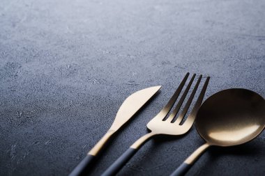 Altın kaşık, çatal, bıçak ve temiz boş siyah tabak. Siyah arka planda siyah ve altın çatal bıçak seti. Modaya uygun ve lüks bir yemek. Üst Manzara. Metnin için boşluk kopyala.