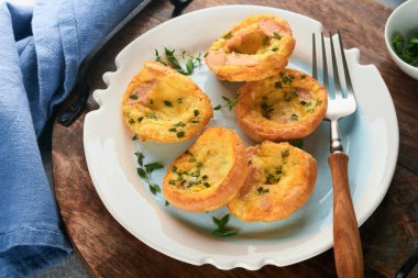 Beyaz tabakta yeşil soğanlı yumurta kekleri, pastırma, peynir ve domates. Sağlıklı yüksek protein ve düşük karbonhidratlı kahvaltı, yemeye hazır..