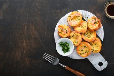 Yeşil soğanlı, pastırmalı, peynirli ve domatesli nefis yumurtalı kekler ahşap ahşap arka planda. Sağlıklı yüksek protein ve düşük karbonhidratlı kahvaltı. Ev yapımı yemek..