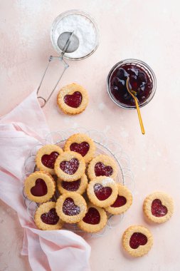 Geleneksel Linzer kurabiyesi, pembe arka planda çilek reçeli ve pudra şekerli. Üst Manzara. Sevgililer Günü 'nde ev yapımı Avusturya tatlı yemeği. Bayram atıştırmalığı konsepti.
