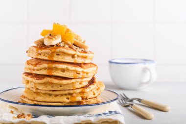 Krepler. Hafif beton zeminde kahvaltıda muz, ceviz ve karamel ile ev yapımı pofuduk krep. Geleneksel Amerikan kahvaltısı için leziz krepler. Seçici odaklanma. Model.