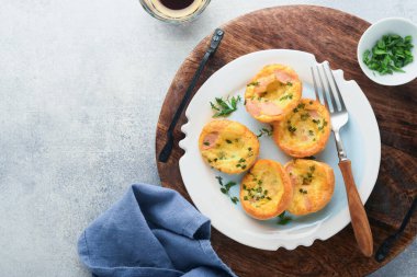 Beyaz tabakta yeşil soğanlı yumurta kekleri, pastırma, peynir ve domates. Sağlıklı yüksek protein ve düşük karbonhidratlı kahvaltı, yemeye hazır.. 