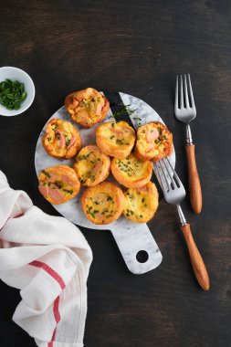 Yeşil soğanlı, pastırmalı, peynirli ve domatesli nefis yumurtalı kekler ahşap ahşap arka planda. Sağlıklı yüksek protein ve düşük karbonhidratlı kahvaltı. Ev yapımı yemek..