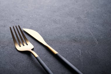 Altın kaşık, çatal, bıçak ve temiz boş siyah tabak. Siyah arka planda siyah ve altın çatal bıçak seti. Modaya uygun ve lüks bir yemek. Üst Manzara. Metnin için boşluk kopyala.