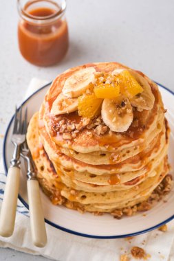 Krepler. Hafif beton zeminde kahvaltıda muz, ceviz ve karamel ile ev yapımı pofuduk krep. Geleneksel Amerikan kahvaltısı için leziz krepler. Seçici odaklanma. Model.